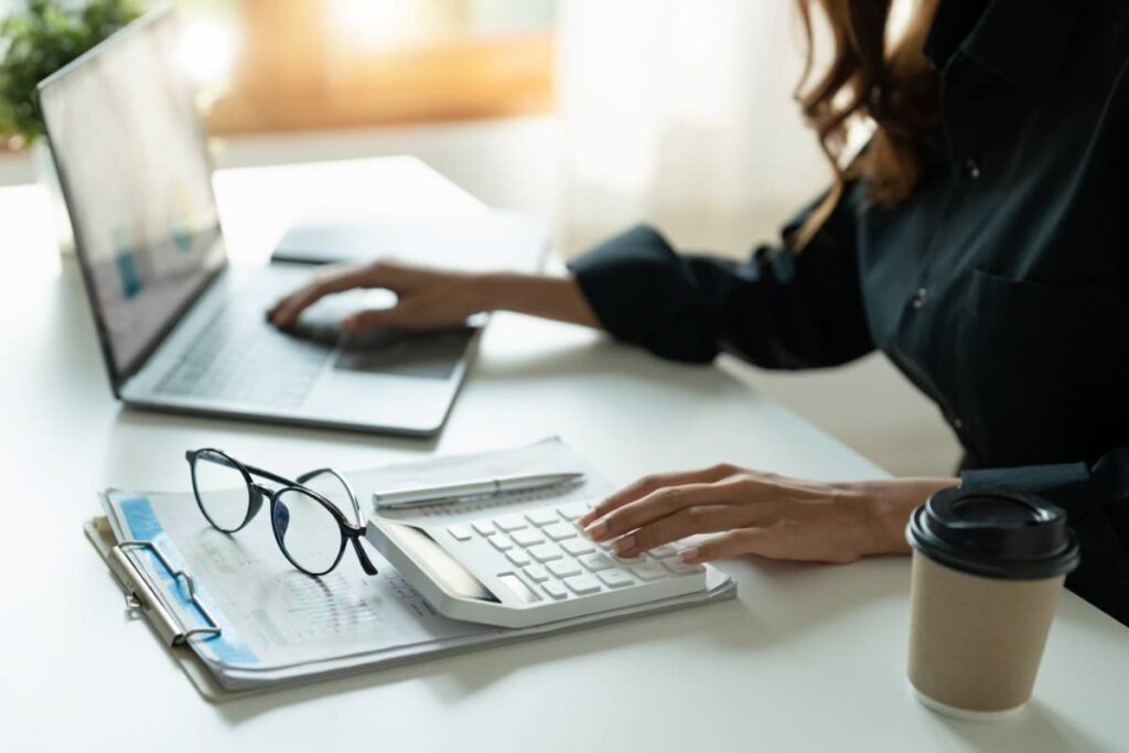 Profissional fazendo a gestão de contas e contratos no notebook com calculadora.