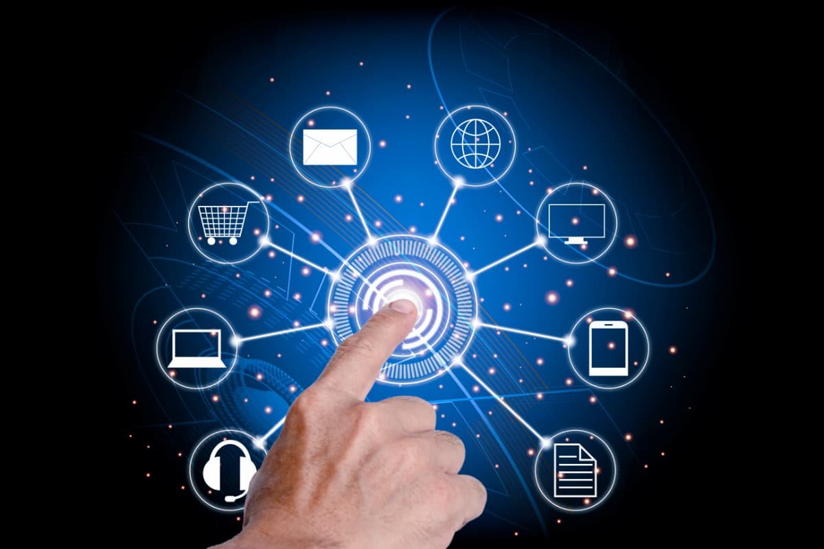 Mão tocando ícone de marketing digital em interface futurista com ícones de e-mail, globo e carrinho.