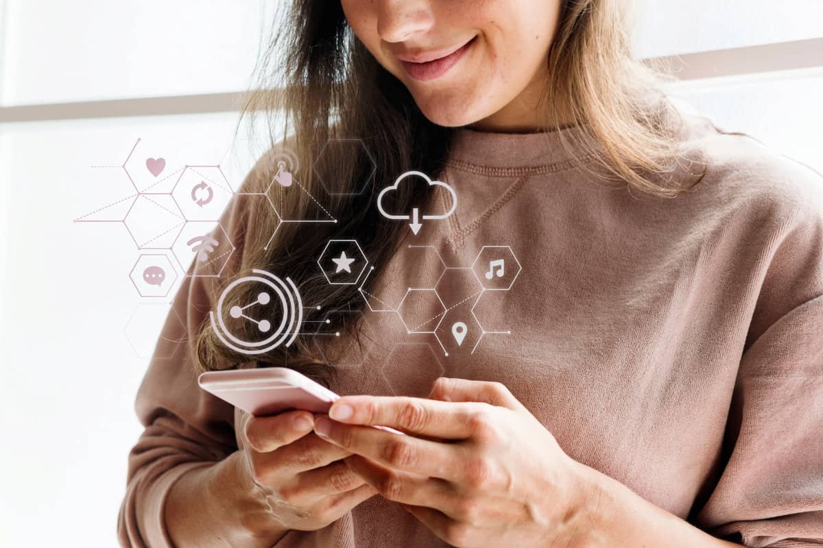 Mulher usando smartphone com ícones de Internet das Coisas flutuando ao redor, simbolizando conectividade e tecnologia inteligente.