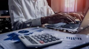 Pessoa trabalha em notebook e com calculadora para entender o custo padrão e custo real