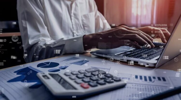 Pessoa trabalha em notebook e com calculadora para entender o custo padrão e custo real