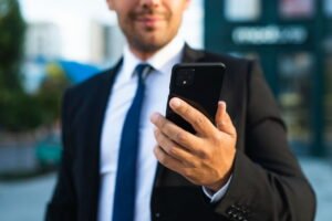 Homem de terno segura celular enquanto pesquisa como bloquear conteudo improprio no celular empresarial