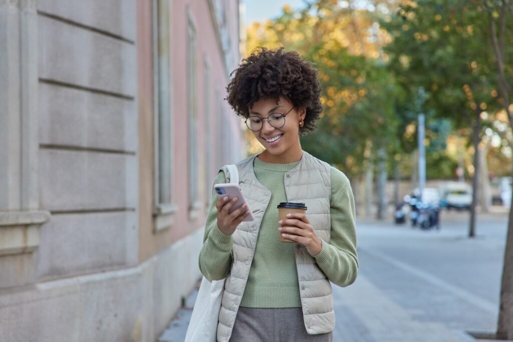 Pessoa de cabelo cacheado segurando o celular